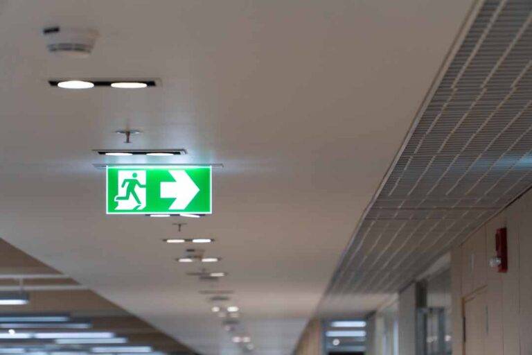 Green Fire Escape Sign Hang On The Ceiling In The Office.