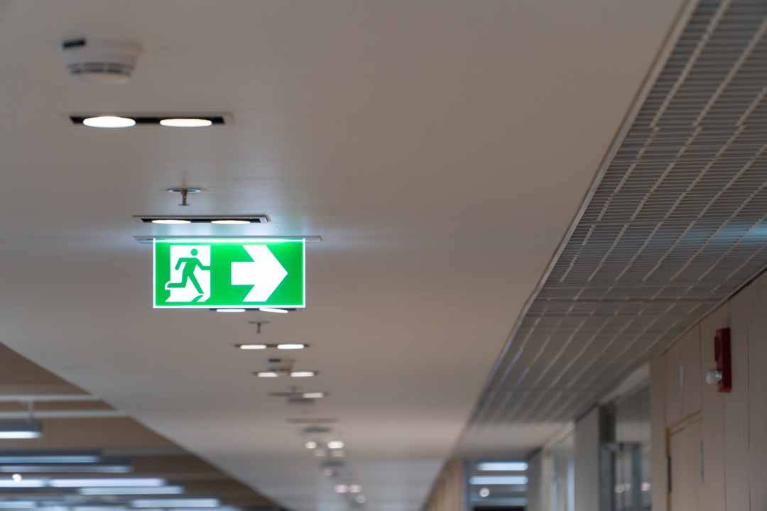 Green Fire Escape Sign Hang On The Ceiling In The Office.